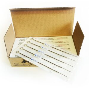 Öppnad pappkartong innehållande sterilt förpackade tatueringsnålar av klassisk typ.