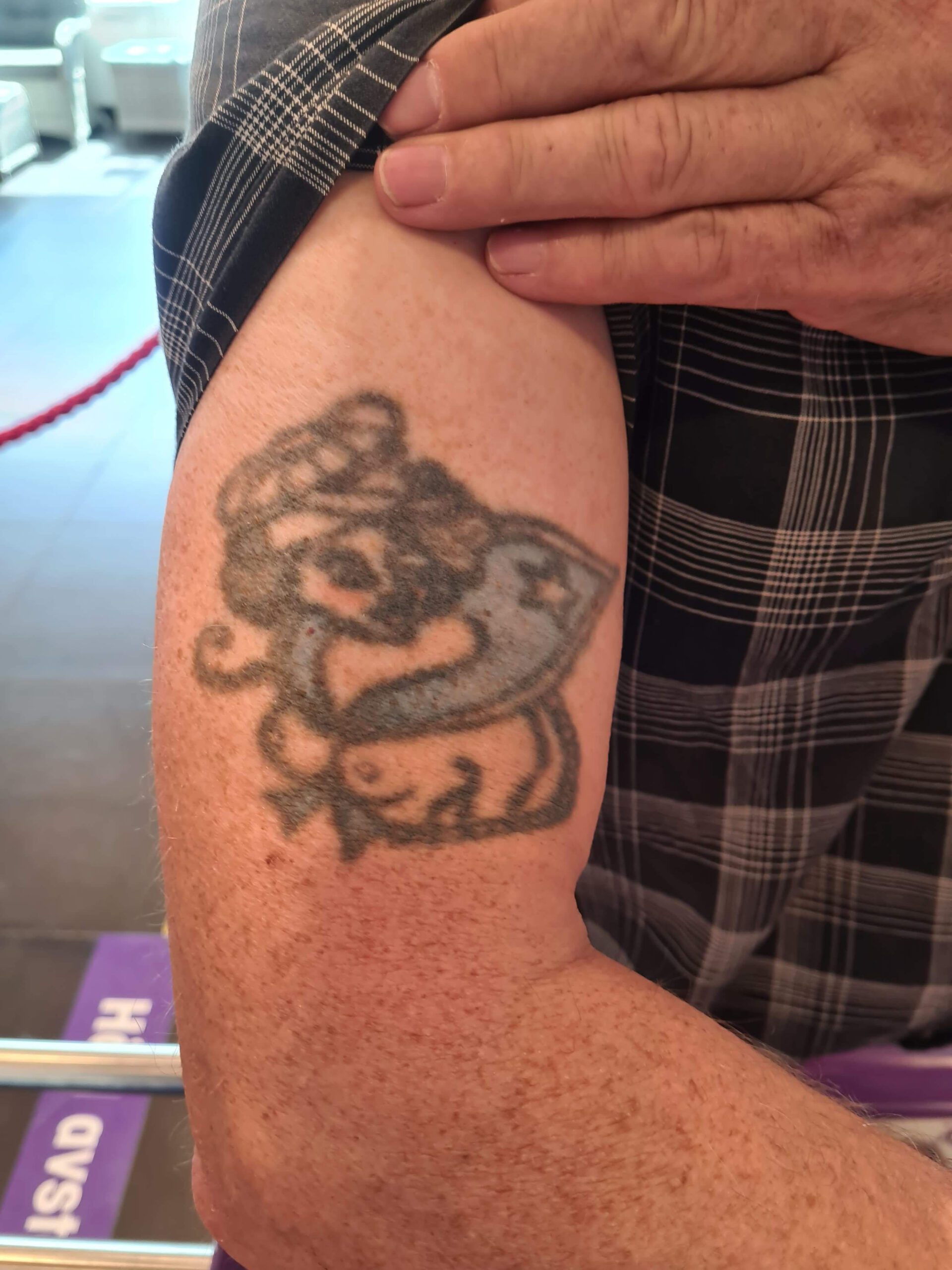 Överarmstatuering med barbröstad pinuppa, byst, iklädd matrosmössa och -halsduk.