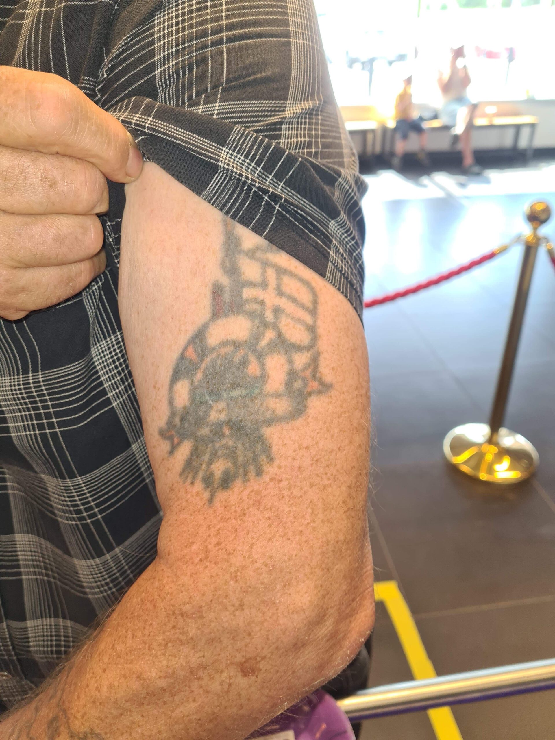 Överarmstatuering med flagga, rigg och livboj.