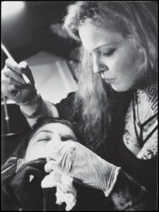 Svartvitt fotografi av Habba Nero handstickande hakan på liggande klient.