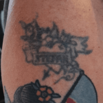 Överarmstatuering med hjärta, blommor och banderoll, med namnet: Stefan.