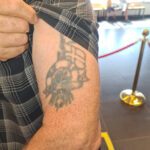 Överarmstatuering med flagga, rigg och livboj.