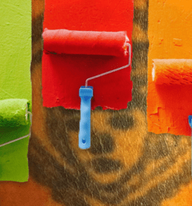 Manipulerad kollagebild av målarrollers som rollar grön, röd och orange färg över en äldre tatuering.